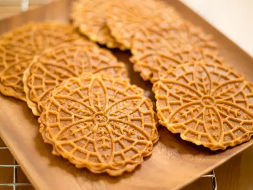 Pizzelle, dolci tradizionali abruzzesi, su un piatto di legno.