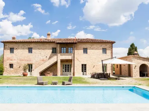 Splendida villa in pietra con piscina, un sogno di masserie toscane sotto un cielo azzurro.