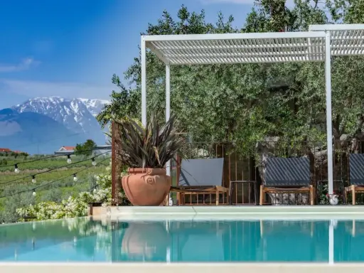 Piscina con vista sulle montagne innevate, ideale per una vacanza in Abruzzo montagna. Relax sotto il pergolato tra ulivi secolari.