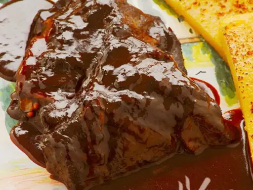 Succulento stracotto di manzo in salsa scura, servito con polenta dorata. Un classico della ricetta dello stracotto.