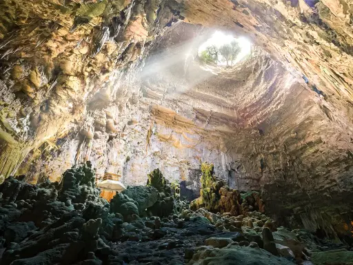 Grotta con stalattiti e stalagmiti illuminate da un raggio di sole. Un luogo magico da scoprire tra le cose da vedere vicino Alberobello.