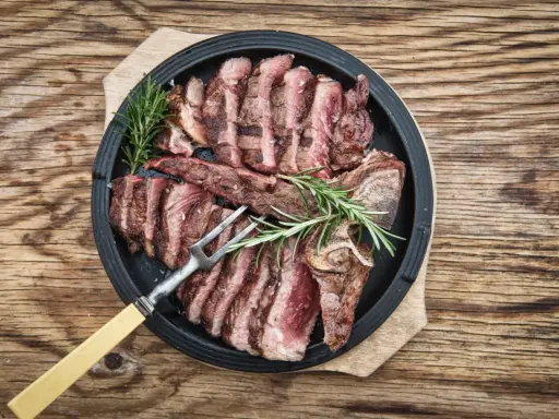 Una succulenta bistecca fiorentina affettata, guarnita con rosmarino, pronta per essere gustata.