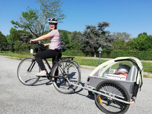 Donna in bici con rimorchio per bambini, pronta per le vacanze in bici con bambini.