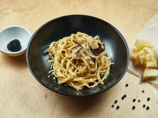 Un piatto di pasta al tartufo, un sapore autentico del cibo perugino, con scaglie di parmigiano e pepe nero.
