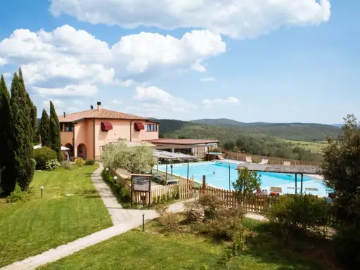Un agriturismo in Toscana a Pasqua, con piscina azzurra e colline verdi sullo sfondo.