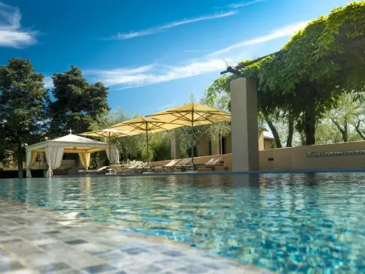 Piscina con lettini e ombrelloni in un agriturismo particolare nel Lazio, immerso nel verde.