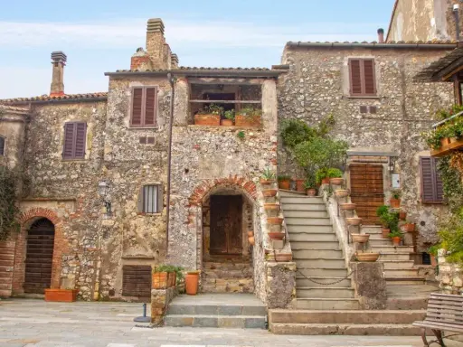 Un angolo di **Toscana, cosa vedere: borghi** antichi con case in pietra, scale fiorite e un'atmosfera senza tempo.