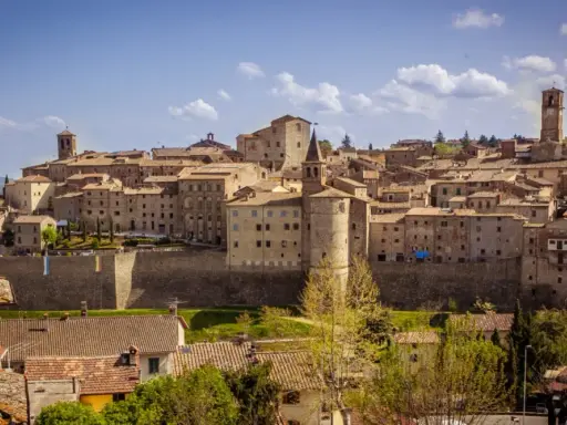 Panoramica di un borgo medievale toscano, con case in pietra e tetti in cotto, che si estende su una collina. Una dettagliata cartina borghi toscana potrebbe mostrare questo luogo.