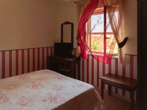 Camera accogliente in un agriturismo a Lamezia Terme, con letto fiorato e tende rosse che danzano al vento.
