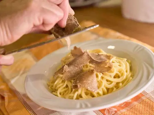 Un piatto di spaghetti conditi con tartufo fresco, un'esperienza culinaria tipica delle sagre tartufo toscana.
