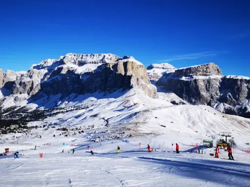 Piste innevate e maestose vette per decidere dove andare a sciare in Trentino. Sciatori e impianti di risalita animano il paesaggio.