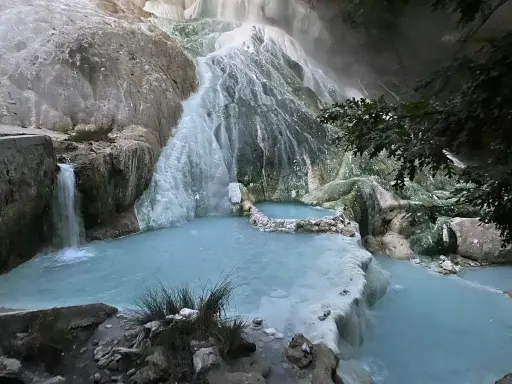 Cascate termali naturali a San Filippo, Toscana, con acque azzurre che scorrono su rocce calcaree.