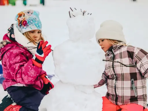 Bambini creano un pupazzo di neve in montagna, un vero natale in montagna con bambini che si divertono nella neve.