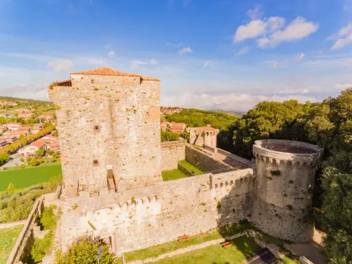 Il castello di Sarteano domina il borgo con le sue mura antiche e torri imponenti, circondato dal verde della campagna toscana.