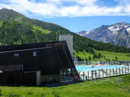 Una splendida piscina in montagna in Piemonte, con vista su verdi colline e cime innevate.