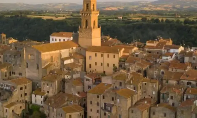 Pitigliano, la "piccola Gerusalemme", si staglia su una rupe tufacea, con le sue case antiche e la torre campanaria che domina il paesaggio.
