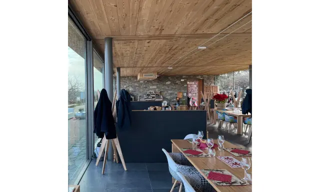Interno di un agriturismo con tavoli apparecchiati, bancone in pietra e legno. L'agriturismo acqua terra sole offre un'atmosfera accogliente.