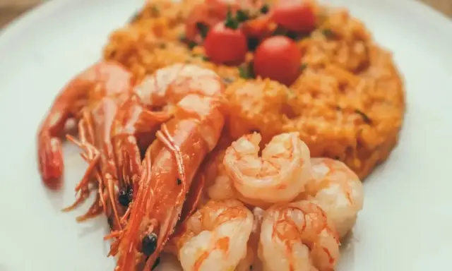 Risotto rosso con gamberi, un piatto tipico di Pavia, guarnito con pomodorini freschi.