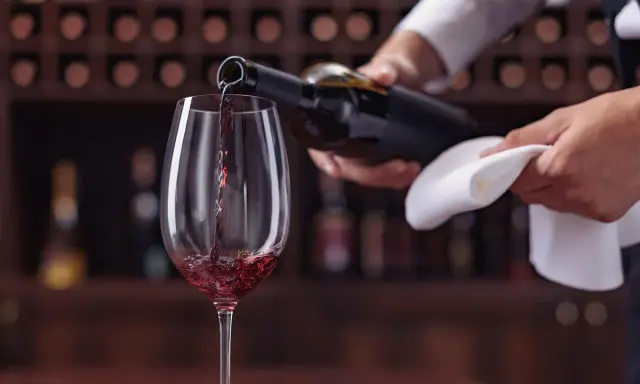 Un calice di vino rosso viene versato da una bottiglia, un momento perfetto per un tour enogastronomico Toscana.