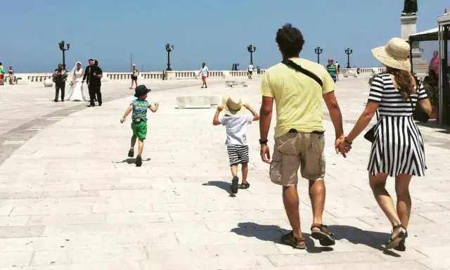 Famiglia in vacanza in Puglia con bambini, mentre passeggiano sul lungomare.