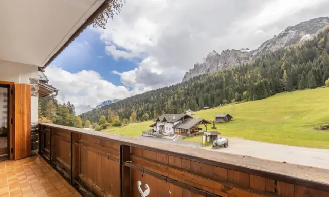 Vista da un balcone su una casa di montagna con prati verdi e boschi. Perfetta per una vacanza in montagna estate.