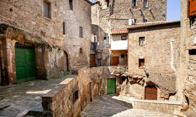Un vicolo stretto con scale di pietra e case antiche in tufo, un'atmosfera da piccola Gerusalemme.