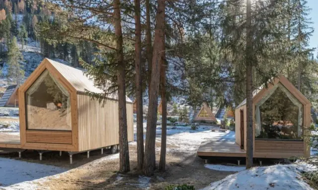Accoglienti alloggi particolari nel Lazio, con cabine in legno e ampie vetrate immerse nel bosco innevato.