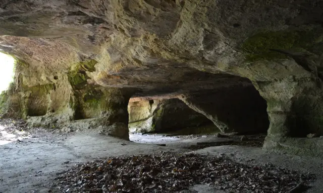 L'interno di una grotta scavata nella roccia, con nicchie e passaggi che ricordano Vitozza, la città perduta.