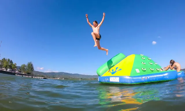 Bambini si divertono sul lago Trasimeno, uno salta da un gonfiabile mentre un altro si riposa.