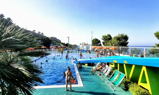 Sole, piscina e divertimento al camping Riva Verde Marche. Famiglie e bambini si godono l'acqua cristallina e il relax sotto gli ombrelloni.