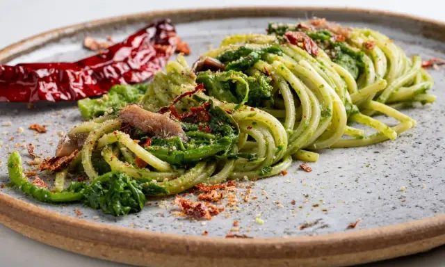 Spaghetti verdi con verdure, acciughe e peperoncino secco, un piatto tipico Basilicata che evoca sapori autentici.