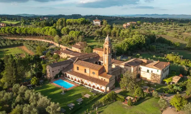 Un'antica dimora con campanile e una splendida piscina toscana, immersa nel verde delle colline.
