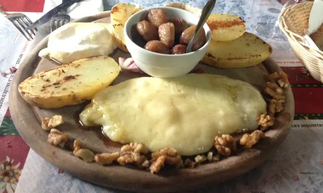 Piatto con formaggio fuso, patate arrosto, noci e cipolline. Un assaggio dei piatti tipici Valle d'Aosta.