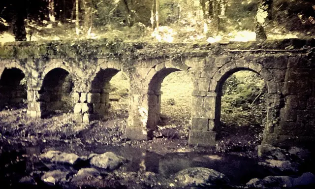 Antica struttura in pietra con archi, forse un acquedotto o un ponte, immersa nel verde. La **vitozza Sorano** sembra un luogo dimenticato dal tempo.