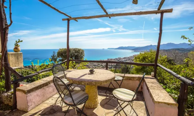 Terrazza con tavolo e sedie, vista mare e colline. Ideale per agriturismi entroterra ligure.