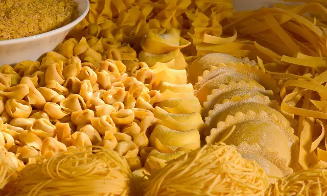 Varietà di pasta fresca, tra cui tortellini, ravioli e tagliatelle, che rappresentano i piatti tipici dell'Emilia Romagna.