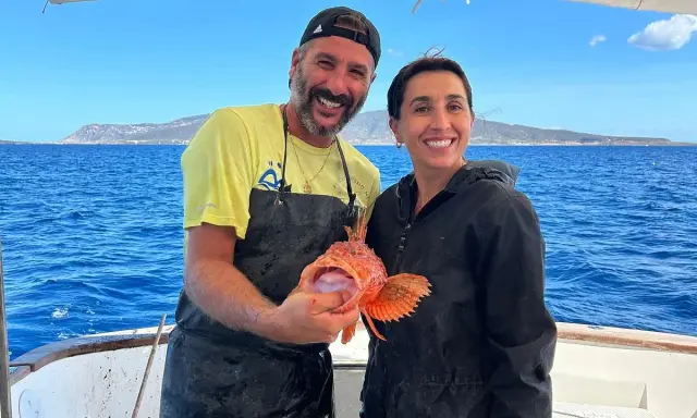 Coppia felice in barca, lui mostra un pesce rosso appena pescato, un'esperienza di pesca turismo indimenticabile.