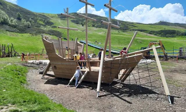 Un grande galeone di legno su un prato verde, perfetto per agriturismi per bambini in Piemonte. Bambini giocano a bordo.