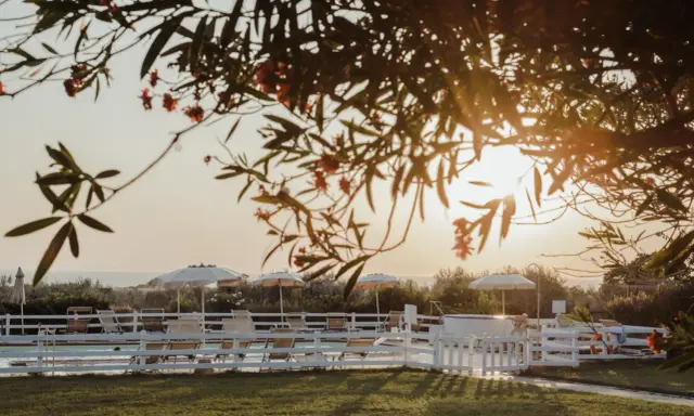 Tramonto dorato su una piscina con lettini e ombrelloni, un'oasi di pace tra i **posti romantici Toscana**.