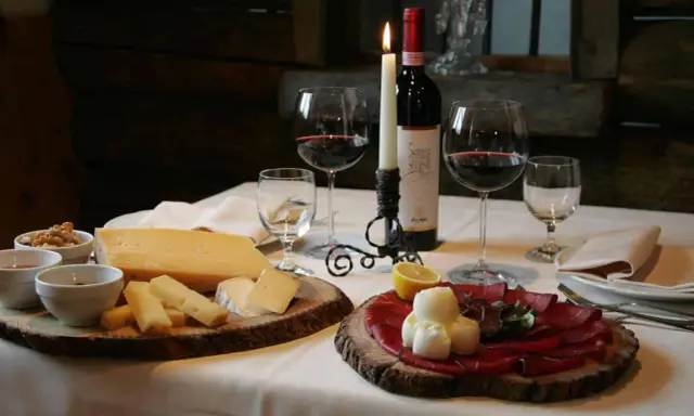 Tagliere con formaggi e bresaola, accompagnati da vino rosso e candela. Un assaggio dei piatti tipici Valtellina.
