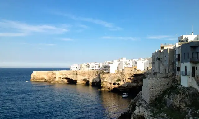 Scogliere bianche e case a picco sul mare blu, un'ottima idea per cosa visitare vicino Alberobello.