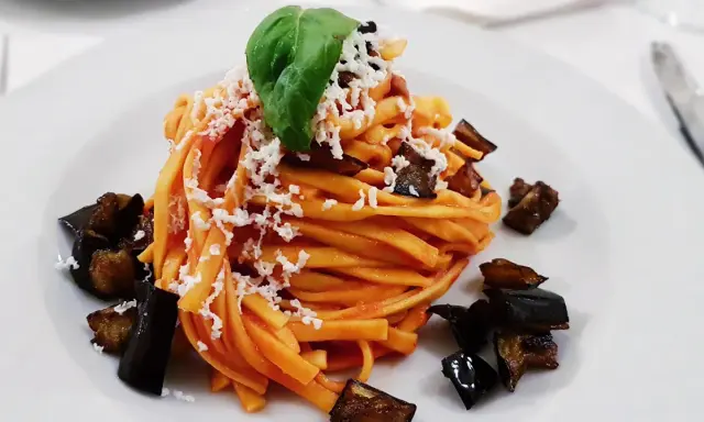 Pasta con melanzane fritte e ricotta salata, un classico su cosa mangiare in Sicilia. Un piatto gustoso e colorato.