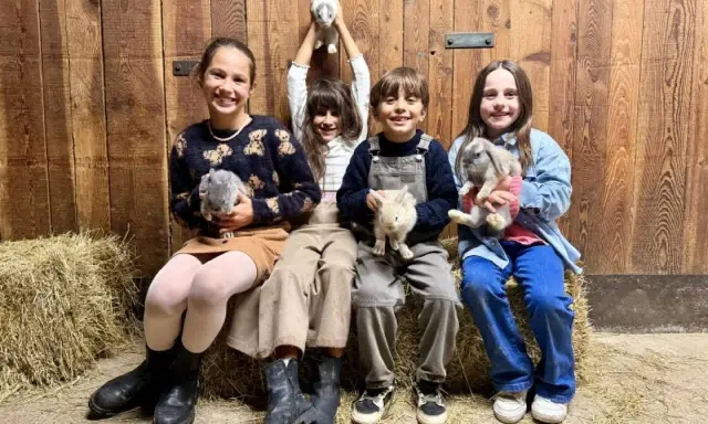 Bambini felici durante un'attività fattoria, tengono in braccio coniglietti soffici.
