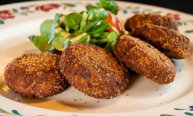 Crocchette dorate e croccanti, un classico su cosa mangiare in Lombardia, servite con un'insalatina fresca.