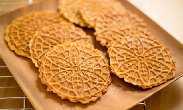Pizzelle, dolci tradizionali abruzzesi, su un piatto di legno.