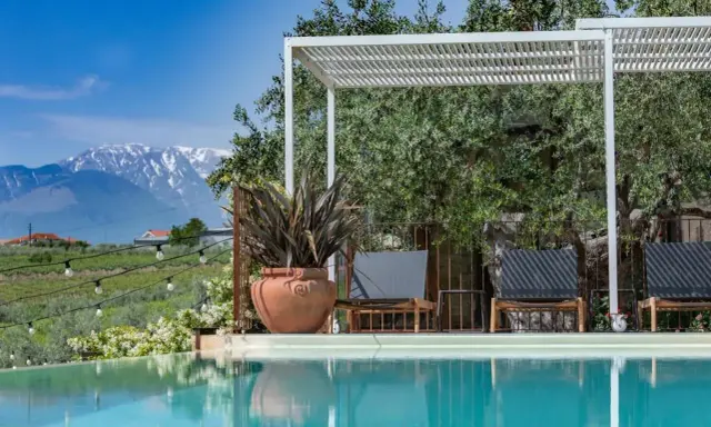 Piscina con vista sulle montagne innevate, ideale per una vacanza in Abruzzo montagna. Relax sotto il pergolato tra ulivi secolari.