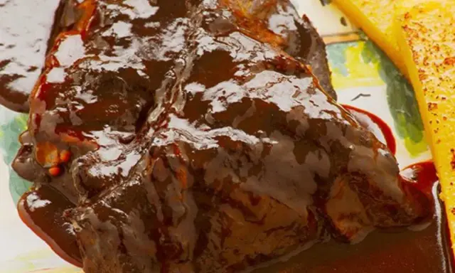 Succulento stracotto di manzo in salsa scura, servito con polenta dorata. Un classico della ricetta dello stracotto.
