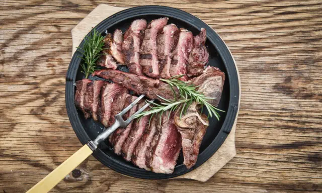 Una succulenta bistecca fiorentina affettata, guarnita con rosmarino, pronta per essere gustata.