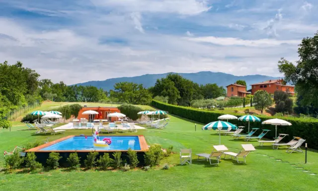 Agriturismi per bambini con piscina e gonfiabile a forma di unicorno, circondati da verde e colline.