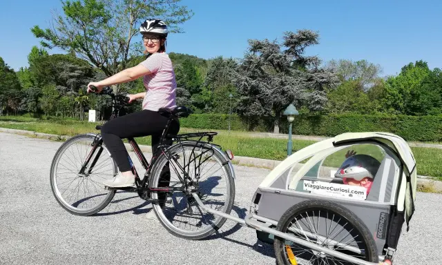 Donna in bici con rimorchio per bambini, pronta per le vacanze in bici con bambini.